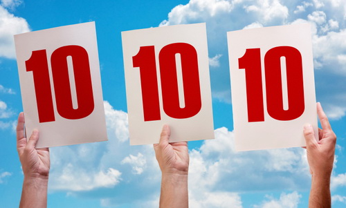 White paper with number ten in male hands on blue sky background
