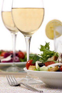 A health dinner salad with lots of greens and white wine