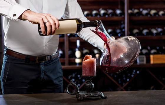 Sommelier pouring wine to the decanter in the wine cellar