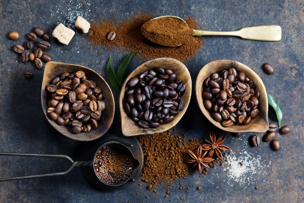 Top view of three different varieties of coffee beans on dark vintage background