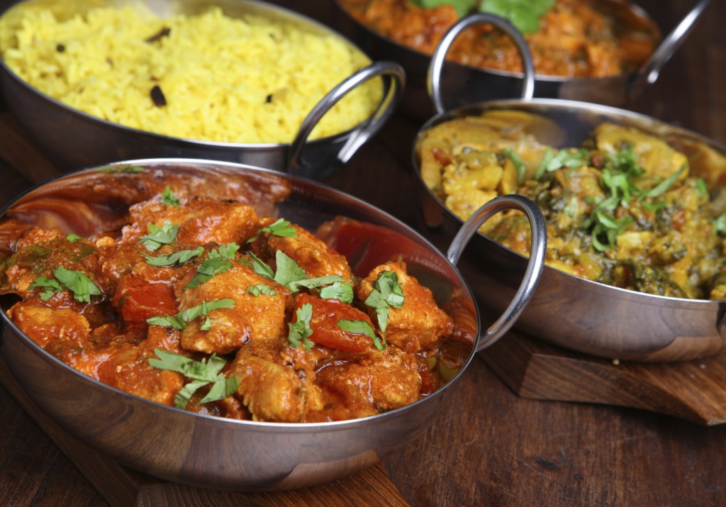 Indian chicken jalfrezi with saag aloo and rice. Shallow DoF, focus on nearest curry.