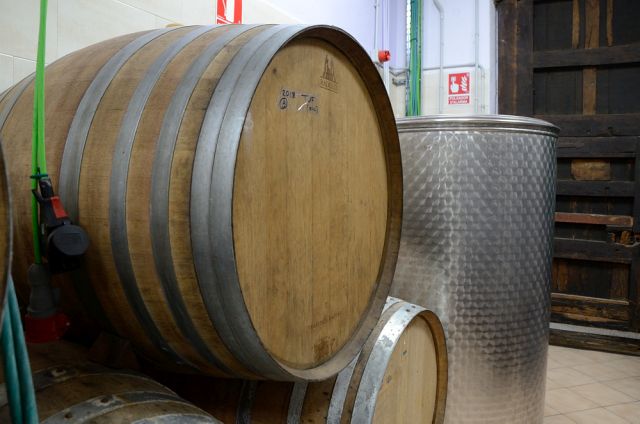 Wooden wine barrel beside a stainless steel tank in Alvarez Duran wine cellar.